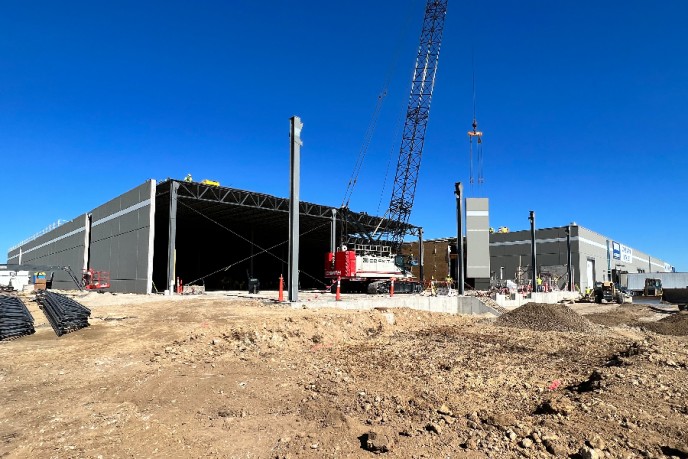 A crane relocates a wall panel to the new south wall of the expansion